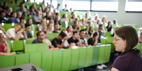Dozierende sitzt vor Studierenden im Hörsaal im Seminargebäude. 